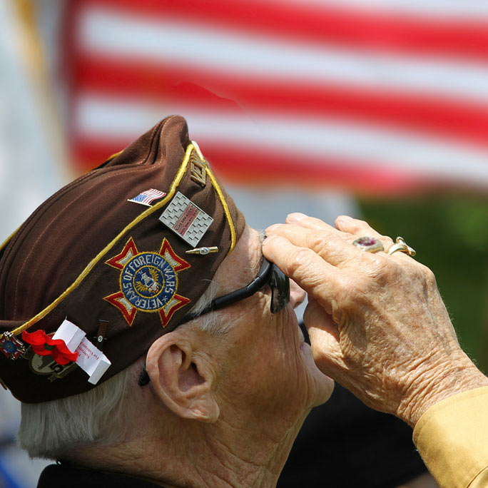 Older male veteran saluting flag