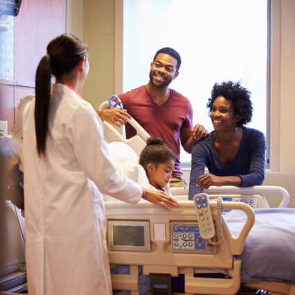 Girl in hospital bed with parents sitting near.