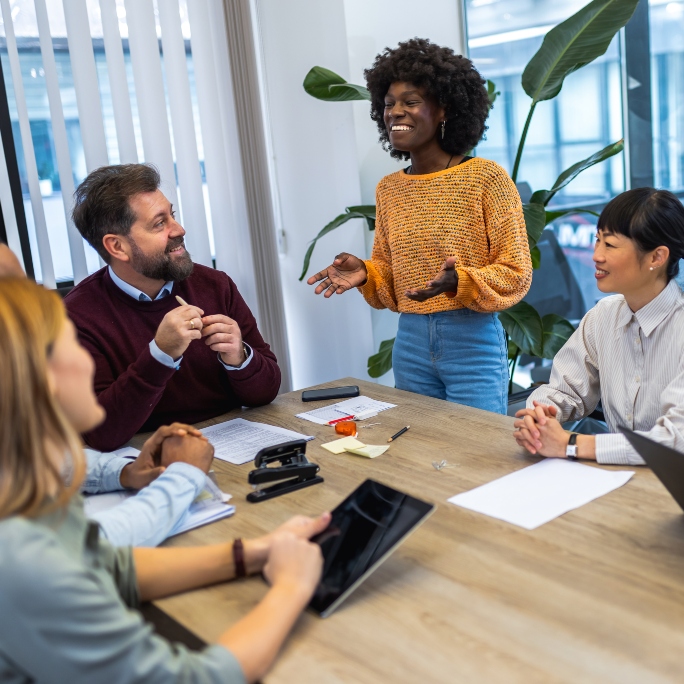 Group of diverse employees sitting around a table in an office setting.