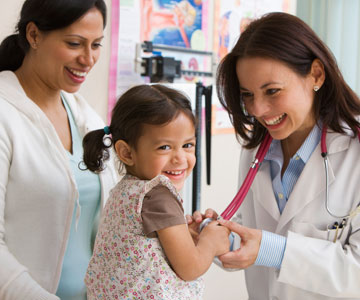 A doctor examines a little girl during a well-child visit.